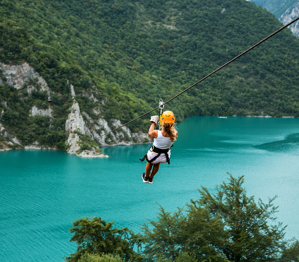 Woman sliding on a zip line over the blue lake