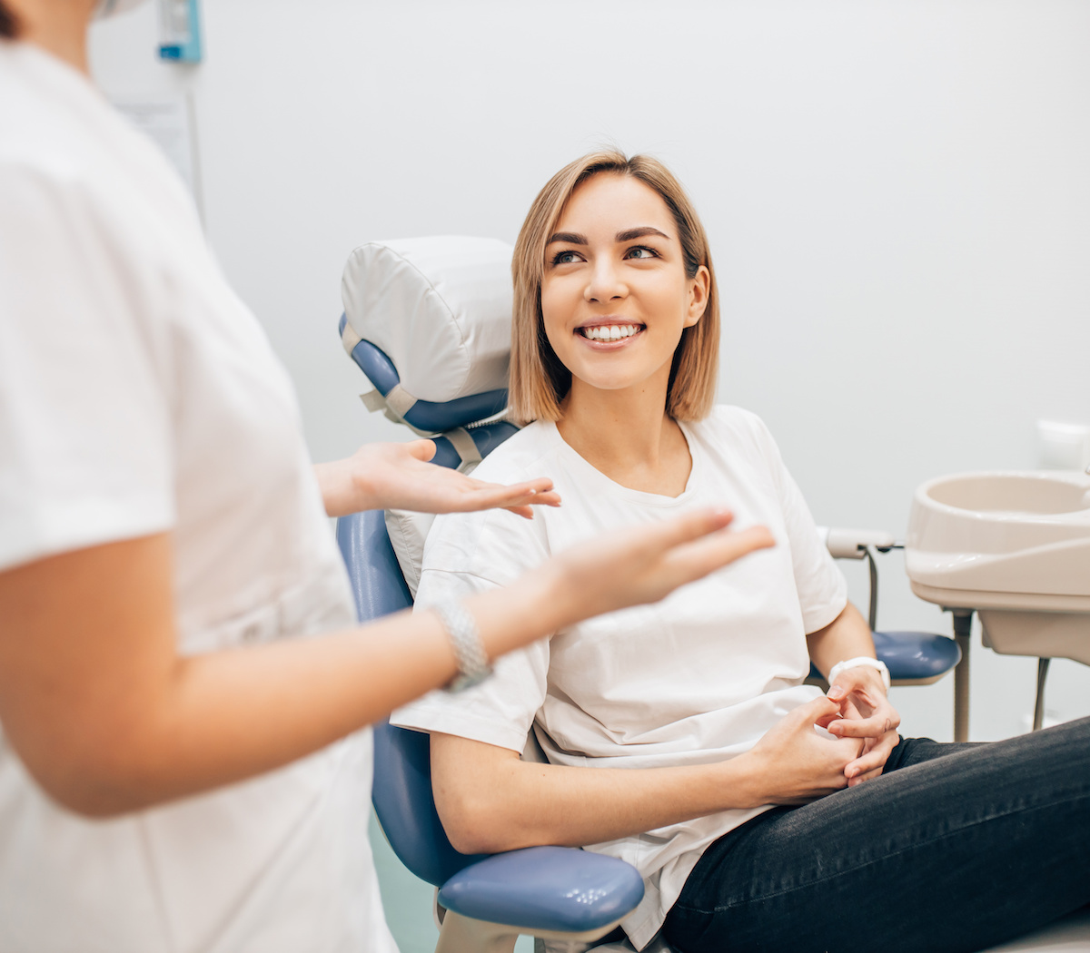 Dental marketing: Woman sits in dentist's chair as technician talks