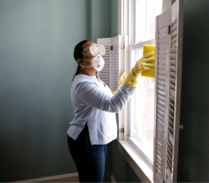 woman wearing safety mask cleaning window
