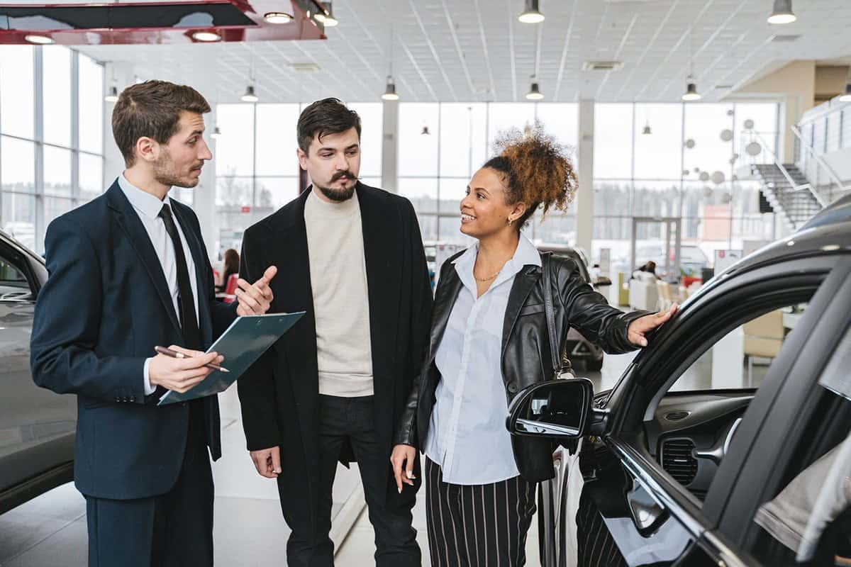 salespeople talking to customers at car dealership